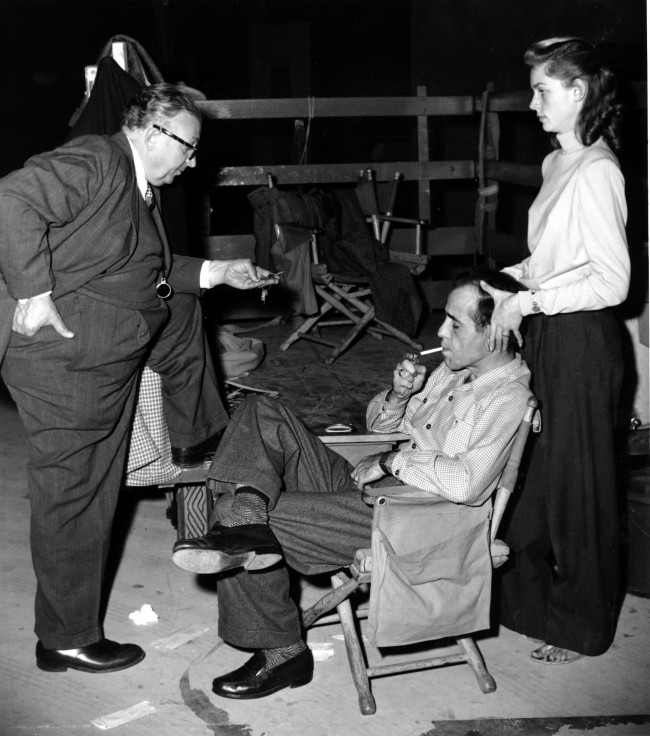 Actor Humphrey Bogart, lighting cigarette, actress Lauren Bacall, massaging her husband's head, and cameraman Karl Freund relax on the set of "Key Largo" in Hollywood, Ca., on Jan. 19, 1948. (AP Photo)