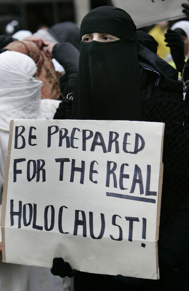 A veiled Muslim protester, holding a placard, marches towards the Danish embassy during a demonstration in London, Friday Feb. 3, 2006. Hundreds of people protested against the publication of cartoons in nespapers around Europe depicting the Prophet Muhammad. (AP Photo/Lefteris Pitarakis)