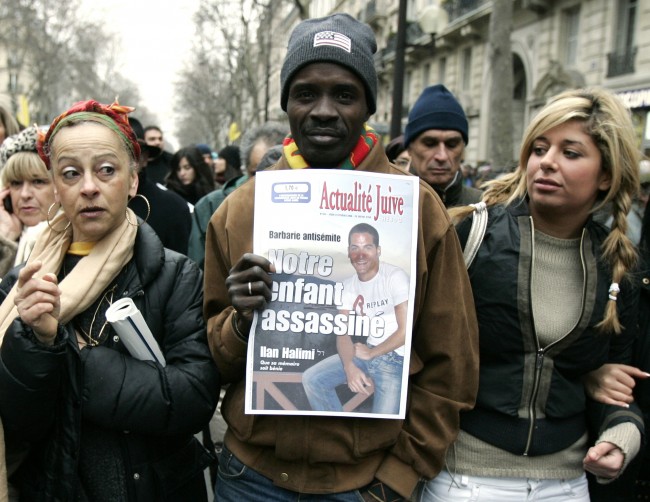 Demonstrators take part in a march in Paris, the French capital, Sunday, Feb. 26, 2006 to show opposition to racism and anti-Semitism after the brutal killing of Ilan Halimi, a Parisian Jew, seen in the placard. The sign says in French says "Our child murdered". (AP Photo/Francois Mori)