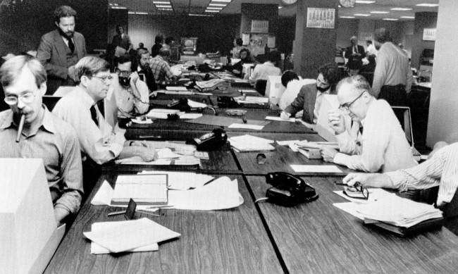 The newsroom at the New York Times is seen as editorial staffers work feverishly to prepare a Monday edition, in this Nov. 5, 1978 file photo. A reader-submitted question related to how newsrooms are alerted to breaking news stories is being answered as part of an Associated Press Q&A column called "Ask AP." (AP Photo/Ron Frehm, File)