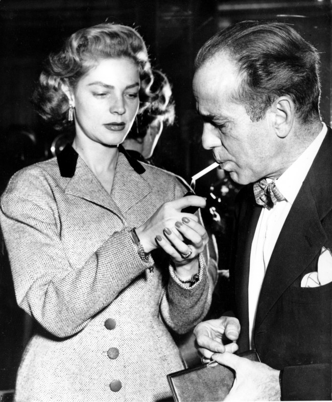 Actress Lauren Bacall lights a cigarette for her husband, actor Humphrey Bogart, at a press reception at London's Claridges Hotel, England, on April 16, 1951. (AP Photo)