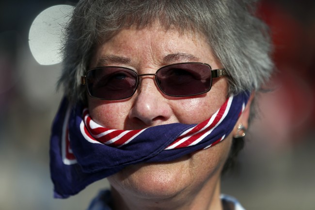 A free speech campaigner uses a British flag as a gag during a protest opposite the Houses of Parliament in central London, Tuesday, Oct. 8, 2013.