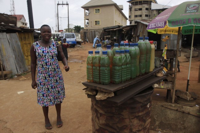 In this photo taken Wednesday, Feb. 29, 2012, an Igbo woman walks past engine oil displayed for sale on a street in Nnewi, Nigeria. Assaults by a radical Islamist sect known as Boko Haram have sent many Igbo people to flee the north even as state officials and others downplay the exodus, likely out of fear of sparking retaliatory violence. (AP Photos/Sunday Alamba)