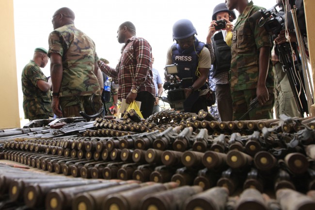 In this Wednesday, June 5, 2013 file photo, journalists look at arms and ammunition which military commanders say they seized from Islamic fighters, in Maiduguri, Nigeria, on Wednesday, June 5, 2013. Boko Haram, the radical group that once attacked only government institutions and security forces, is increasingly targeting civilians. Some 155,000 square kilometers (60,000 square miles) of Nigeria are now under a state of emergency. On Friday, June 21, 2013, villagers streamed into Maiduguri from the Gwoza hills, saying Boko Haram fighters were threatening a bloodbath in the area where they appear to have regrouped, scrubby mountains with rock caves some 150 kilometers (90 miles) from the city. (AP Photo/Jon Gambrell, File)