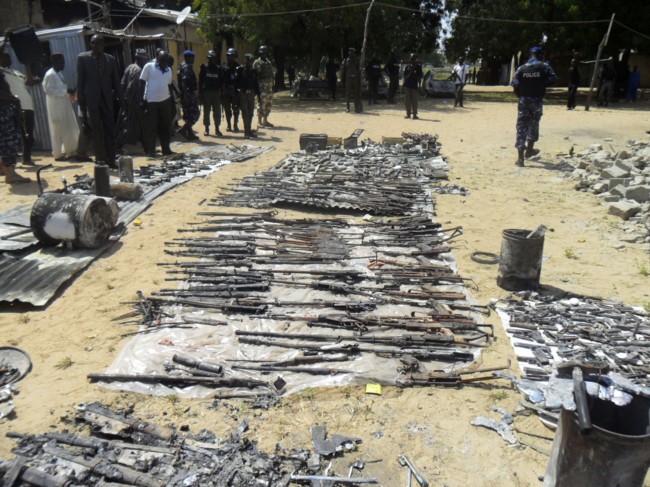 In this photo taken on Monday, Oct. 28, 2013, people inspect burnt weapons following an attack by Boko Haram in in Damaturu, Nigeria. Nigerian military and hospital reports indicate a 5-hour-long battle between Islamic extremists and troops in the capital of NigeriaÂs Yobe state last Thursday and Friday killed at least 90 militants, 23 soldiers and eight police officers. (AP Photo)