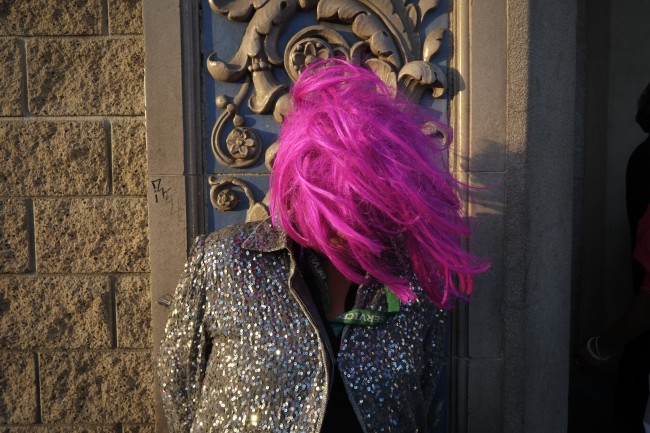 A homeless woman wears a wig while waiting for the start of a karaoke night outside a church in the Skid Row area of Los Angeles, Wednesday, May 15, 2013. (AP Photo/Jae C. Hong)