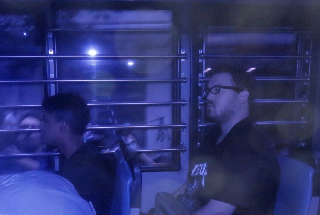 Rurik George Caton Jutting, 29, right, is escorted by police officers in an police van after his appearing in a court in Hong Kong Monday, Nov. 3, 2014. Hong Kong police said Monday that they had charged the 29-tear-old British man with killing two women, including one whose body was found inside a suitcase on the balcony of the man's upscale apartment. (AP Photo/Vincent Yu)