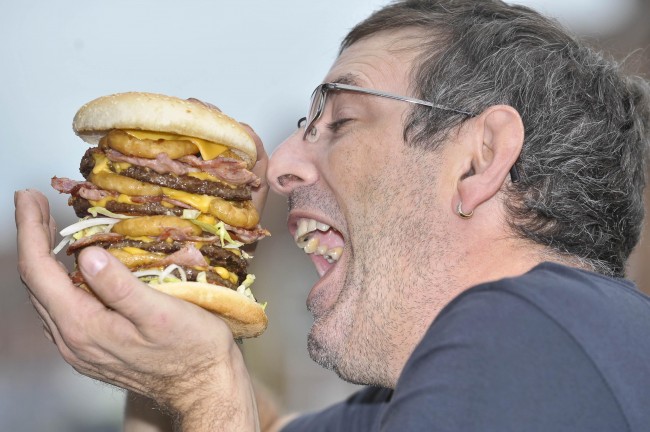 Karl Ford, aged 40, from Shirehampton, Bristol, who is a burger chef and creator of the 'Super Scooby' burger, Britain's largest and most fattening burger with an artery-busting 2,645 calories, holds his super sandwich. Picture date: Monday September 28, 2009. The 'Super Scooby' is made and sold by the Jolly Fryer takeaway in Bristol and they are offering customers the gut-busting burger, with chips, for 10 - and a free can of Diet Coke to anyone who can finish it, including the chips, in one sitting. The sandwich is loaded with four beefburgers, eight rashers of bacon, eight slices of cheese, 12 onion rings, heaps of salad and three sauces and contains 145 more calories than the daily recommended limit for men. Photo credit should read: Ben Birchall/PA Wire Ref #: PA.7864228  Date: 28/09/2009
