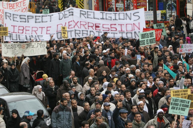 Several thousand Muslims marche through Paris, France, to protest against French newspapers that published cartoons of the Prophet Muhammad, Saturday, Feb. 11, 2006. The white sign in the center says in French "Respect of religions, liberty of expression, no contradiction". France's top national Muslim organization said it was launching legal action against the papers, with efforts likely focused on France Soir and Charlie-Hebdo. (AP Photo/Jacques Brinon)