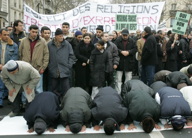 Several Muslims stop to pray whilst marching through Paris, France, to protest against French newspapers that published cartoons of the Prophet Muhammad, Saturday, Feb. 11, 2006. The white sign in the center says in French "Respect of religions, liberty of expression, no contradiction". France's top national Muslim organization said it was launching legal action against the papers, with efforts likely focused on France Soir and Charlie-Hebdo. (AP Photo/Jacques Brinon)