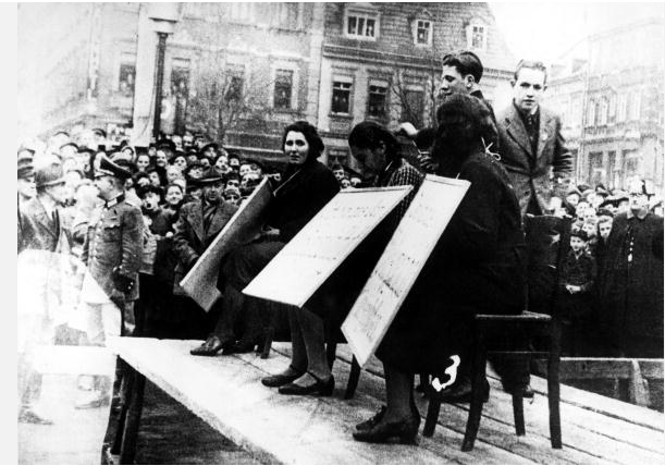 Austria are exhibited in public with a cardboard sign stating 'I have been excluded from the national community (Volksgemeinschaft)', during the anti-Jewish pogrom known as Kristallnacht, November 1938.