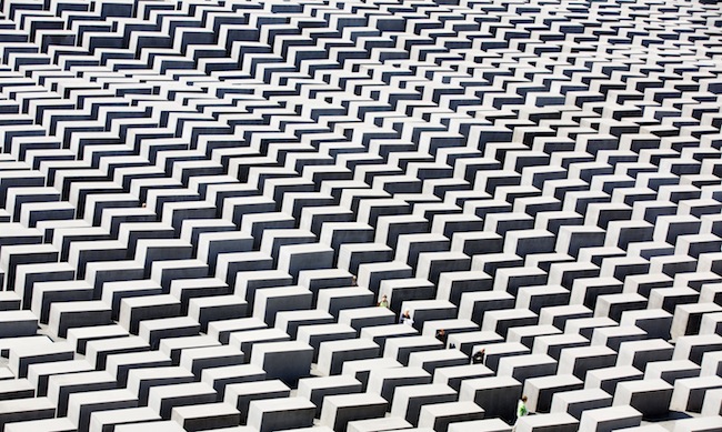 People walk through the concrete steles of the the Holocaust memorial in Berlin, Germany, Monday, Aug. 13, 2012. The memorial to the 6 million Jews killed in Europe under the Nazis was created by U.S. architect Peter Eisenman and consists of an undulating field of 2,711 steles through which visitors can wander. (AP Photo/Gero Breloer)
